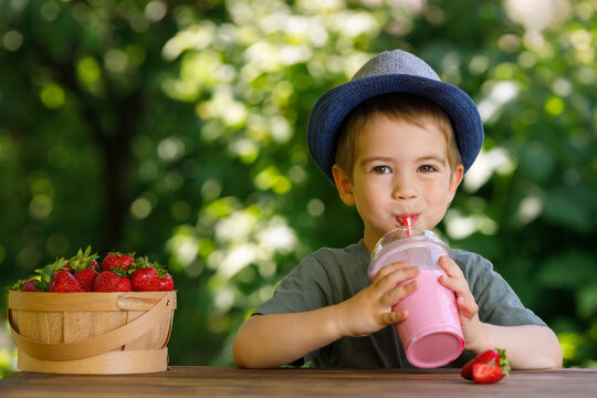 little boy drinking strawberry milkshake from disposable plastic glass