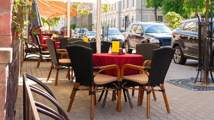 An empty street cafe with no people during the coronavirus pandemic. A cozy table with a red tablecloth in a small cafe without visitors in the morning.