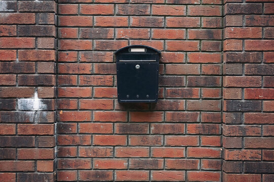 Black mailbox on orange brick wall