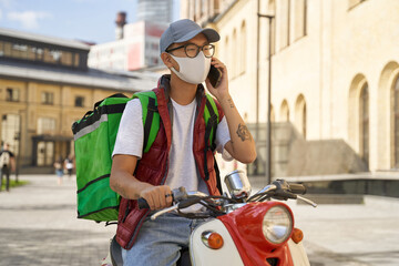 Young asian male courier with thermo bag wearing face protective