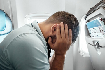A man sits in front of an airplane window and is nervous, afraid to fly, the cabin of a passenger...