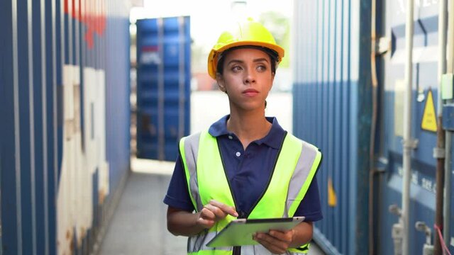 african american  foreman woman using  tablet computer walking to checking and control loading Containers box at warehouse logistic in Cargo . import export freight ship . black worker transportation