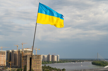 The yellow-blue flag of Ukraine flies in the sky over Kiev and the Dnieper. Beautiful sky. Ukrainian flag