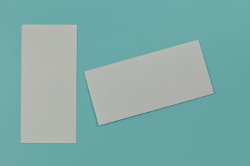 Fototapeta premium Two folded blank paper leaflet on blue background with copy space.