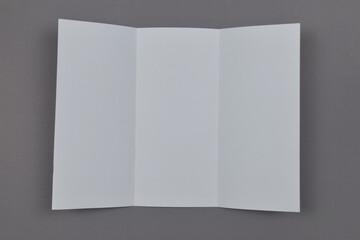 Two folded blank paper leaflet on grey background.