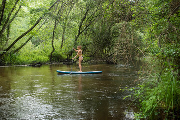 Fototapeta na wymiar beautiful athletic young woman paddling in the middle of a marvelous scenery