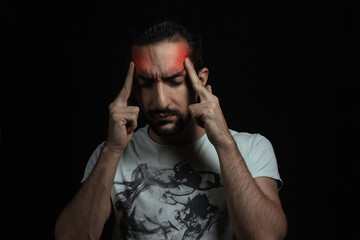 Headache. A man holding his head from a severe headache on a black background.