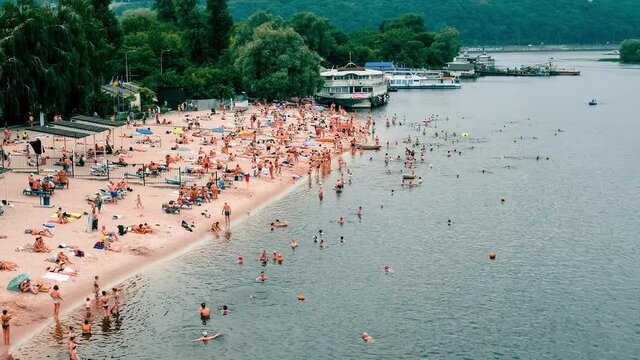KYIV, UKRAINE - JUNE 26, 2021: Picturesque timelapse of beach life in Kyiv city beach. Beautiful green and blue sea waves roll ashore, people swim in the water and sunbathe on the shore.