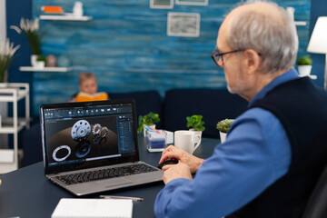 Obraz premium Senior engineer working on deadline sitting at desk. Experienced engineer working from home office on mechanical project using laptop computer technology and wife is reading a book on sofa.