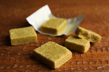 Bouillon cubes with wrap on wooden table, closeup