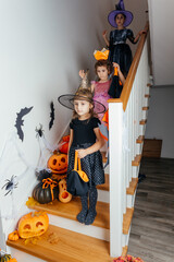 Cheerful girls wearing halloween witch costumes posing on staircase