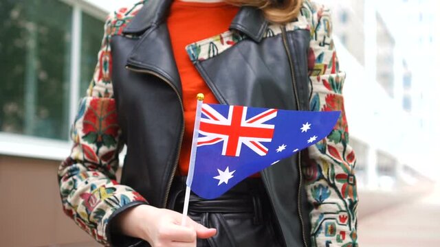 Unrecognizable woman holding Australian flag. Girl walking down street with national flag of Australia