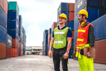 Professional of two engineer container cargo foreman in helmets working standing and using walkie talkie checking stock into container for loading.logistic and business export