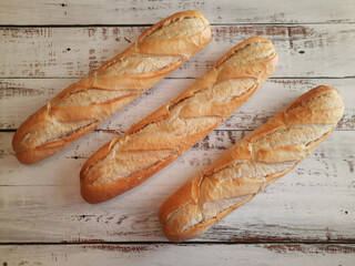 Three loaves of bread close-up on top of aged and white wooden countertop
