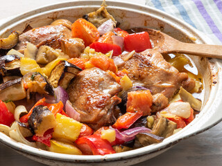 Homemade rustic roast chicken and potatoes with bell pepper in a vintage enamel cast iron pan close-up - greek, bulgarian traditional dish