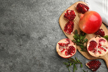 Delicious ripe pomegranates on grey table, flat lay. Space for text