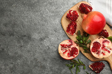 Obraz na płótnie Canvas Delicious ripe pomegranates on grey table, flat lay. Space for text