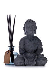 Grey ceramic Buddha statue, standign beside glass home perfume bottle with wooden sticks. Isolated on a white background.