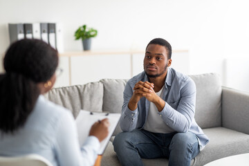 Psychological help service. Depressed male patient having psychotherapy session with counselor at...