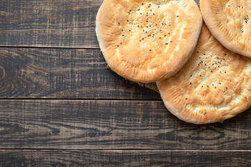 Round unleavened tortillas on a wooden background. Simple rustic sesame bread. Top view, flat lay, copy space.