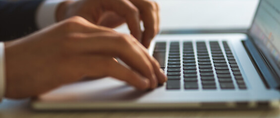 The hands typing on the laptop keyboard