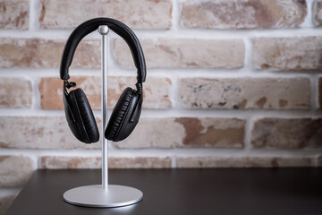 Black headphones on stand against brick wall