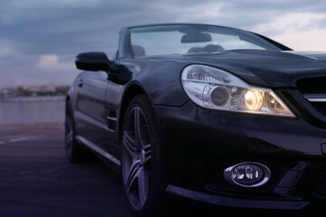 Fototapeta premium Luxury black convertible car outdoors in evening, closeup