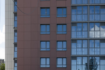Fototapeta premium The facade of a residential building against a background of blue sky and greenery. Construction concept. 