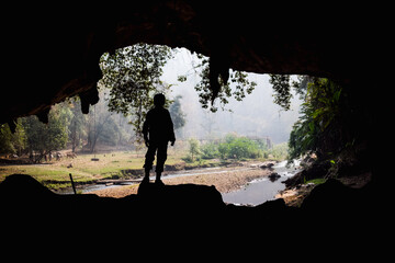 people standing at the entrance to the cave. Outside there are streams and trees.