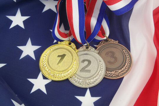 Three medals gold, silver and bronze with ribbons on USA flag.