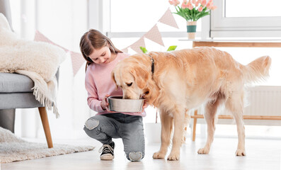 Little girl feeds golden retriever dog
