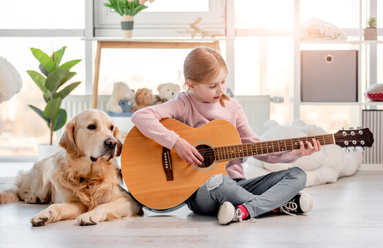 Little girl with guitar and golden retriever dog