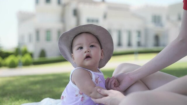 asian woman mother playing with happy baby infant in garden on sunny day under tree on picnic vacation. smile baby happy fun family time.