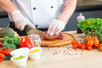Young chef is cutting octopus in a modern kitchen. The man prepares food at home. Cooking healthy and tasty food.