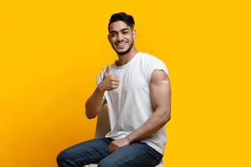 Happy arab man showing arm with band on and thumb up