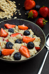 The concept of a healthy breakfast of oatmeal with strawberries and blueberries