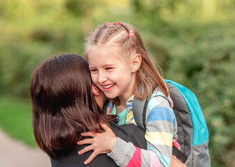 Fototapeta premium School girl hugging mother after classes