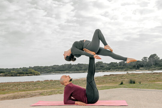 Couple doing acroyoga in a field and a lake