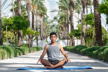 Fototapeta premium latin man meditating with tropical background