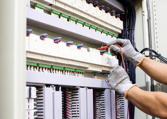 Electrician engineer work tester measuring voltage and current of power electric line in electical cabinet control.	