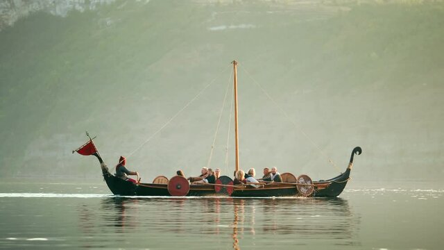 Medieval Ship with Vikings on Board Sails in the Middle of the River in a Magical Fog to new Shores. Concept of Romanticism.