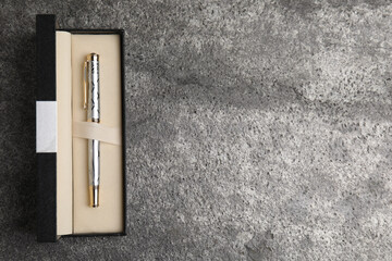 Beautiful ornate fountain pen in box on grey table, top view. Space for text