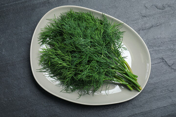 Plate of fresh dill on black table, top view