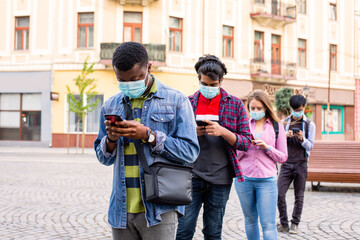 People in masks stand queue keeping social distance