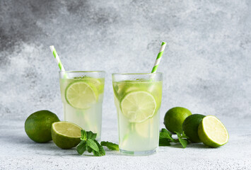 Fototapeta Iced tea with lime. Cold lemonade with lime on a concrete background. obraz