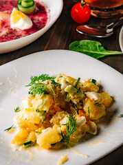 Potato salad with onions and cucumber, mayonnaise-cream dressing in white plate