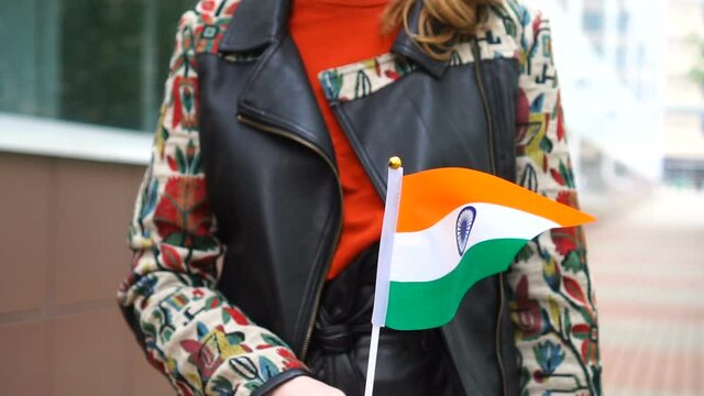 Unrecognizable woman holding Indian flag. Girl walking down street with national flag of India