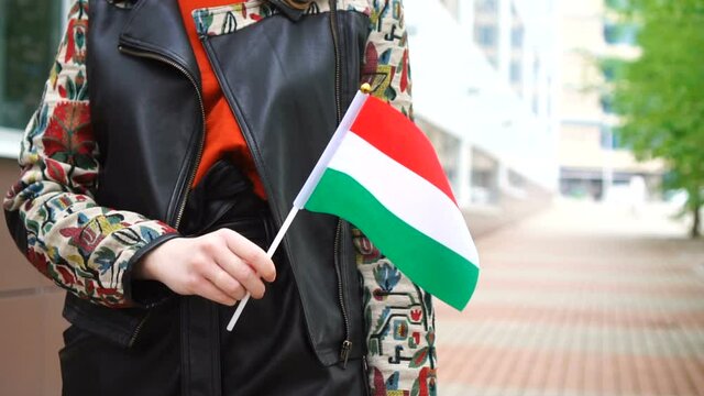 Unrecognizable woman holding Hungarian flag. Girl walking down street with national flag of Hungary