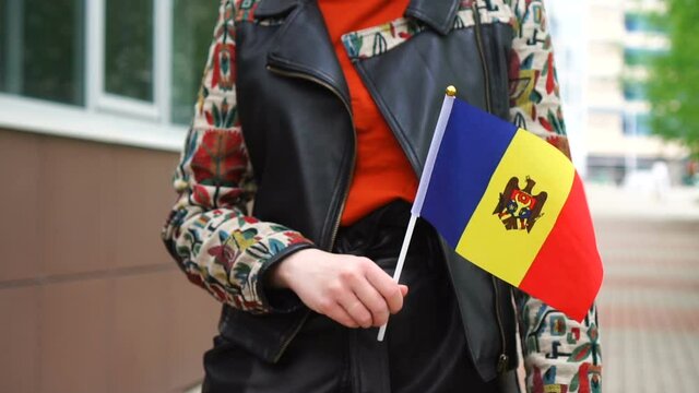 Unrecognizable woman holding Moldavian flag. Girl walking down street with national flag of Moldavia
