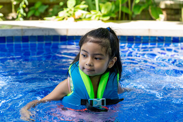 Asian child smilling wearing vest on a swimming pool enjoying swim